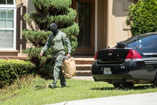 Police officers remove items from a house at 1711 Five Forks Trickum Road that is involved in a massive Gwinnett County drug raid. ALYSSA POINTER / ALYSSA.POINTER@AJC.COM