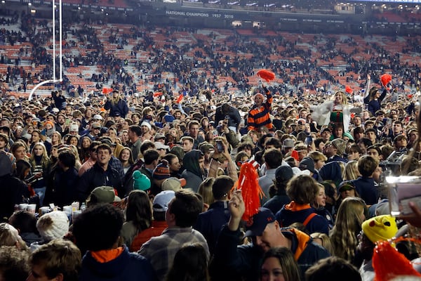 Auburn fans storm the field after defeating Texas A&M during the fourth overtime of an NCAA college football game, Saturday, Nov. 23, 2024, in Auburn, Ala. (AP Photo/Butch Dill)