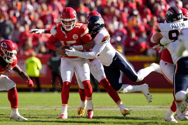 Kansas City Chiefs quarterback Patrick Mahomes (15) is stopped by Denver Broncos outside linebacker Jonathon Cooper, right, during the first half of an NFL football game Sunday, Nov. 10, 2024, in Kansas City, Mo. (AP Photo/Ed Zurga)