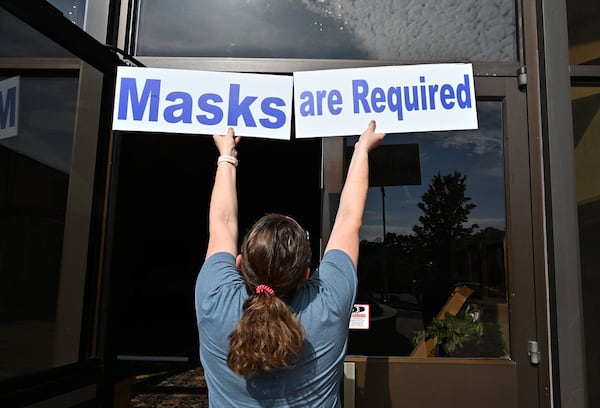 Mary Beth McKenna, director of religious education, posts signs ahead of daily Mass resuming at St. Benedict Catholic Church in metro Atlanta in this AJC file photo. Churches are implementing various safety protocols for services during the pandemic. (Hyosub Shin / Hyosub.Shin@ajc.com)