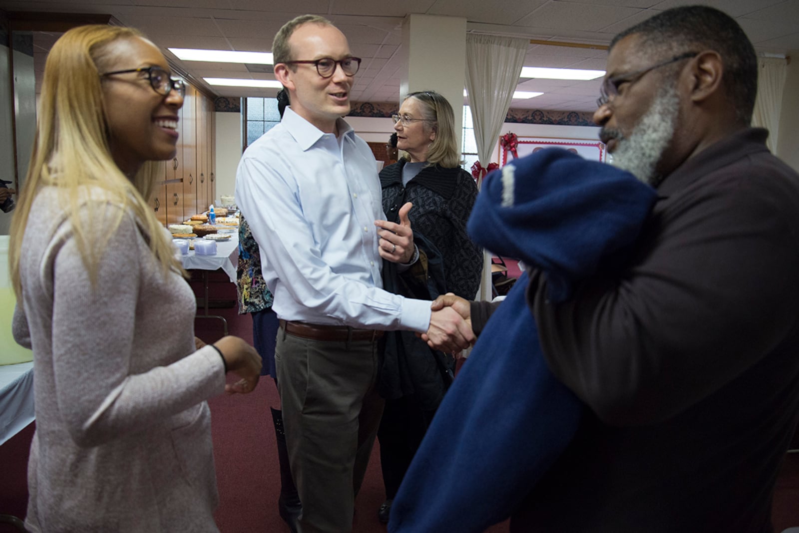 Kenya Hill, Rev. Scott Dickison and Stephen Hill, left to right, talk at First Baptist Church's Thanksgiving Potluck on Sunday, Nov. 19. Kenya and Stephen are parishioners at First Baptist Church on New Street, and Scott Dickison is the reverend at First Baptist Church of Christ on High Place. (Jenna Eason / for the AJC)