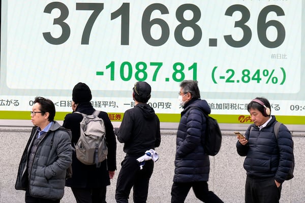 People stand in front of an electronic stock board showing Japan's Nikkei index at a securities firm Friday, Feb. 28, 2025, in Tokyo. (AP Photo/Eugene Hoshiko)