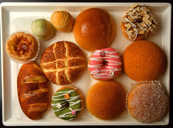 A selection of baked goods from Sweet Hut Bakery & Cafe includes (top row from left) Portuguese egg tart, matcha cream pastry, pineapple pastry, BBQ pork bun, dulce de leche doughnut; (middle row from left) mozzarella cheese bun, cherry amaretto doughnut, Hong Kong polo; (bottom row from left) Thai chili bun, matcha doughnut, curry chicken bun, brown sugar bun.  (CHRIS HUNT FOR THE ATLANTA JOURNAL-CONSTITUTION)