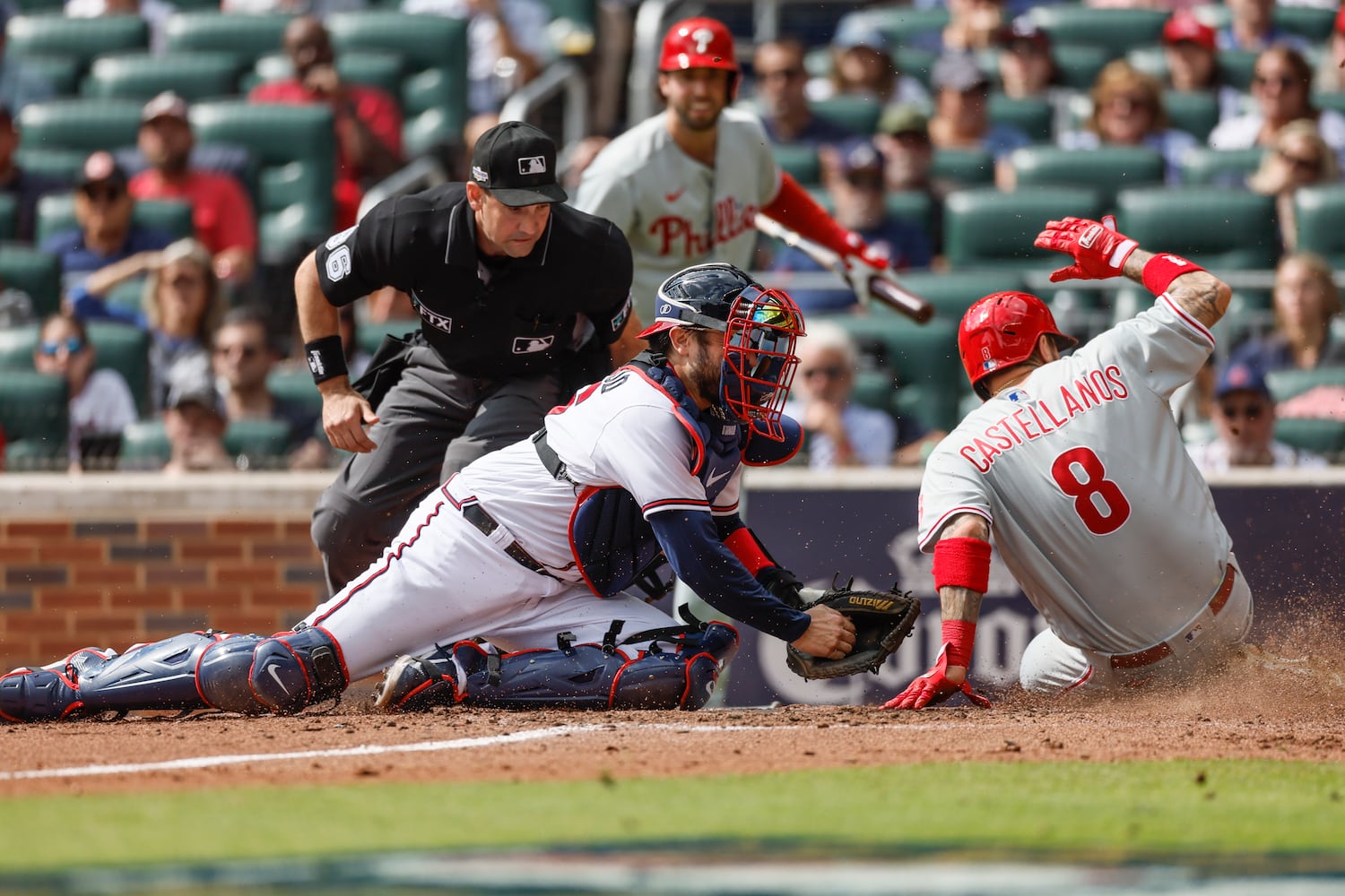 Philadelphia Phillies' Nick Castellanos (8) evades the tag of Atlanta Braves catcher Travis d'Arnaud to score during the third inning of game one of the baseball playoff series between the Braves and the Phillies at Truist Park in Atlanta on Tuesday, October 11, 2022. (Jason Getz / Jason.Getz@ajc.com)