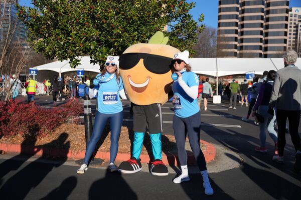 The quintessential peach poses for pictures with runners after the first Polar Opposite Peachtree Road Race. 