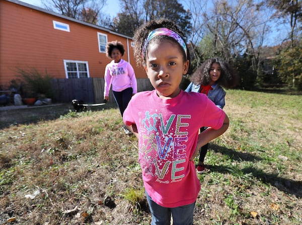 Rosario Hernandez’s granddaughters Aryanna Maymi Booker (from left), 11, Ava Booker, 5, and Aniyah Royal, 9, stand on the vacant lot next to her home where they played and gardened near Mercedes-Benz Stadium on Nov. 25, 2019, in Atlanta. Hernandez discovered slag, a byproduct of smelting, on the property. CURTIS COMPTON / CCOMPTON@AJC.COM