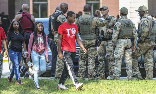 Stephenson High School students walk past DeKalb County SWAT officers outside the school Tuesday morning, Aug. 13, 2019. Officers burst into classrooms with guns drawn after a student reported seeing an armed classmate. The gun scare prompted a heavy police presence, road closures and a Level 3 lockdown at the school on Stephenson Road in Stone Mountain. JOHN SPINK/JSPINK@AJC.COM