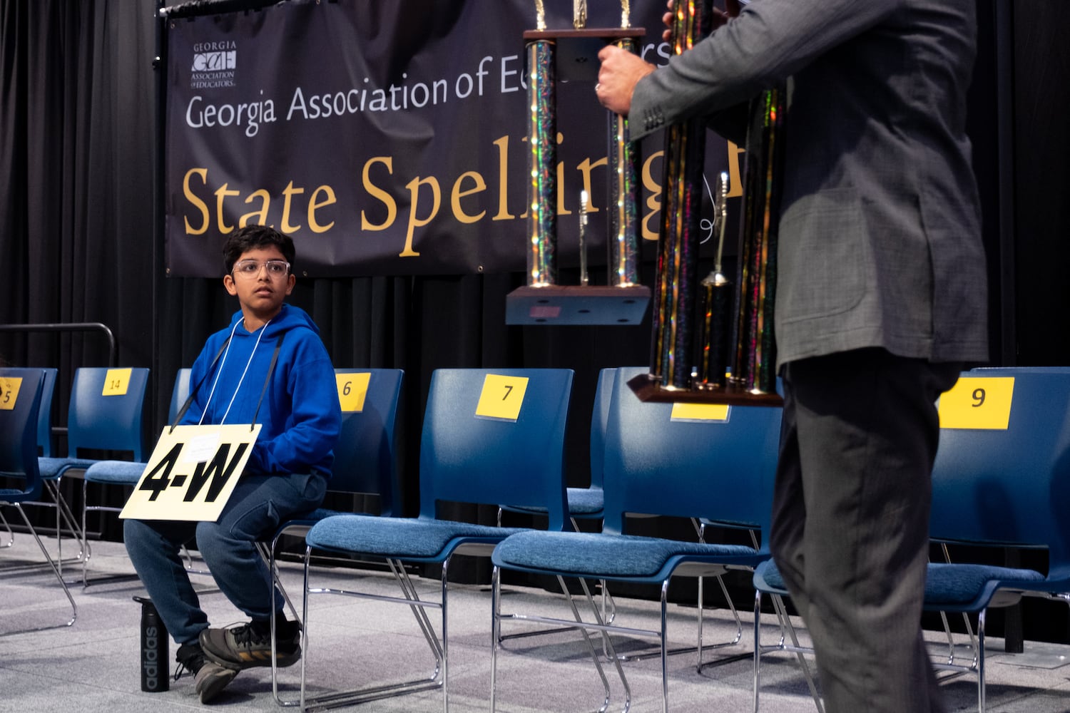 Sarv Dharavane waits to accept his trophy after sinning the GAE State Spelling Bee Championship at Georgia State University in Atlanta on Friday, March 21, 2025.   Ben Gray for the Atlanta Journal-Constitution