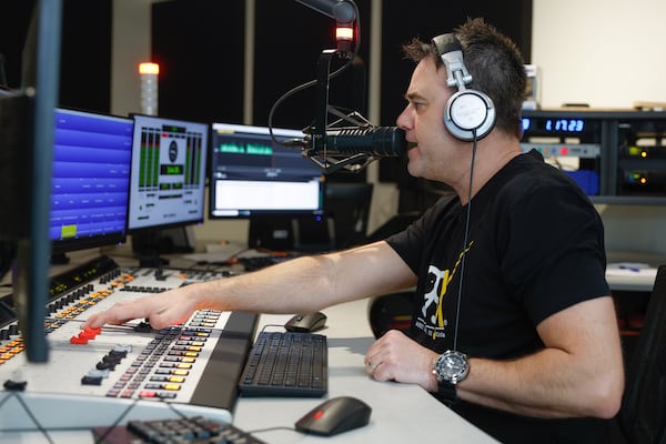 99X radio personality Axel Lowe, who programs the rebooted station, does his afternoon show in the station’s new studio. (Natrice Miller/natrice.miller@ajc.com)