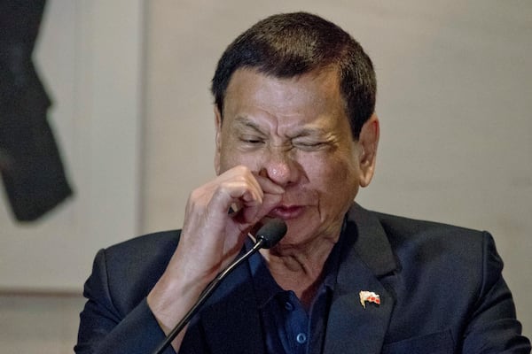 FILE- Philippine President Rodrigo Duterte demonstrates how a drug addict sniffs drugs during a press conference in Beijing, China, Wednesday, Oct. 19, 2016. (AP Photo/Ng Han Guan, File)