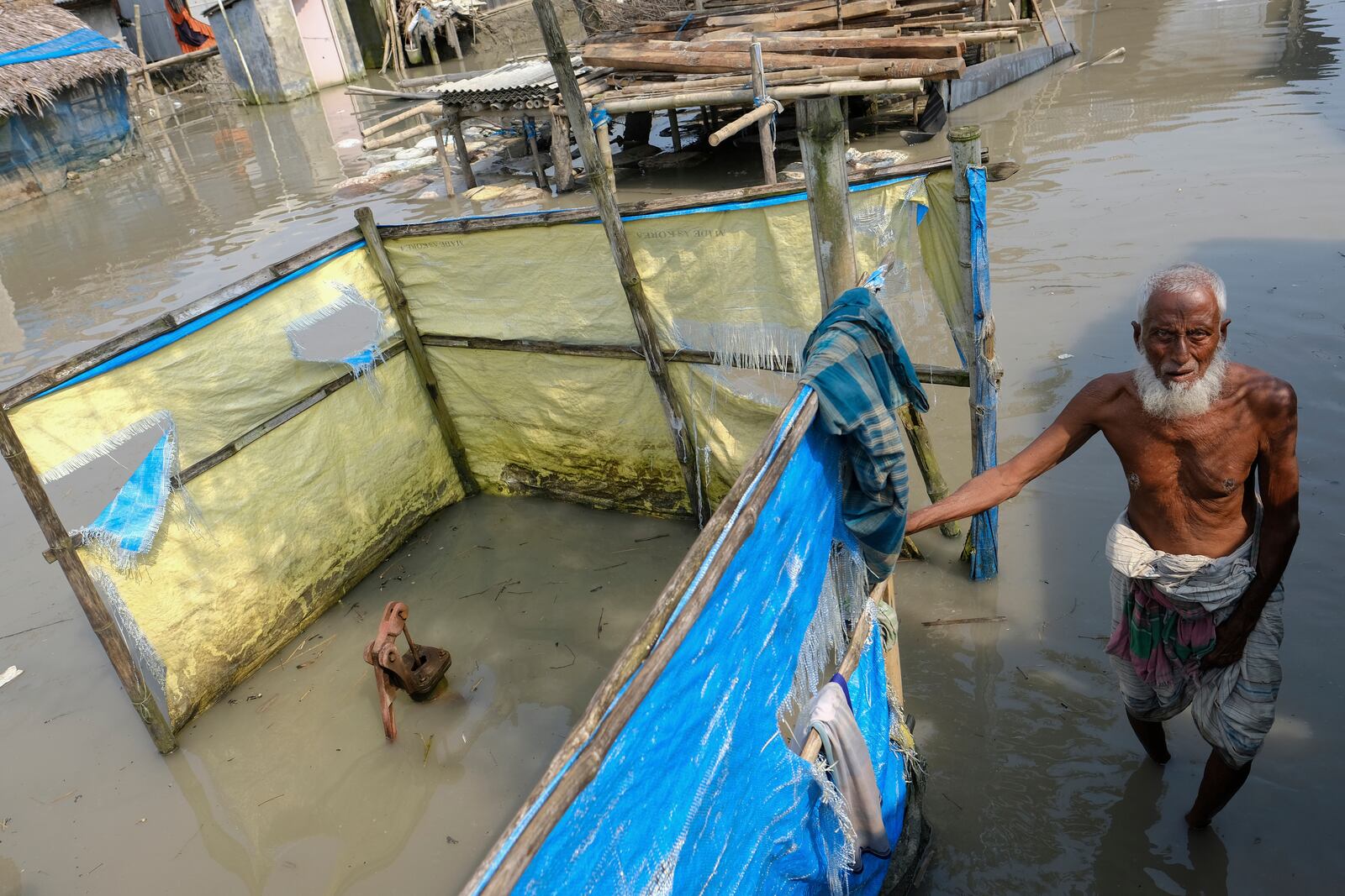 FILE - An elderly man stands by a tube well buried in water during high tide in Pratap Nagar, in Shyamnagar region of Satkhira district, Bangladesh on Oct. 5, 2021. (AP Photo/Mahmud Hossain Opu, File)