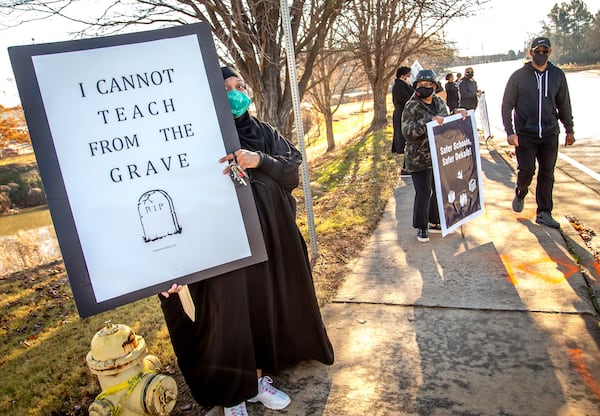 Teacher Amber Horton holds up a sign during a protest in front of the DeKalb school district offices along Mountain Industrial Boulevard in Stone Mountain on Tuesday, Dec. 29, 2020. STEVE SCHAEFER FOR THE ATLANTA JOURNAL-CONSTITUTION