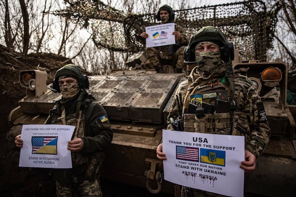 Soldiers of Ukraine's 100th mechanised brigade hold posters saying thanks the US for support during flashmob at the US made APC Bradley on the front line near Toretsk, Donetsk region, Ukraine, Monday, March 10, 2025. (AP Photo/Roman Chop)