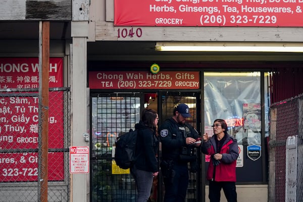 Police officers take a statement from a nearby business owner after multiple people were stabbed Friday, Nov. 8, 2024, in the Chinatown-International District in Seattle. (AP Photo/Lindsey Wasson)