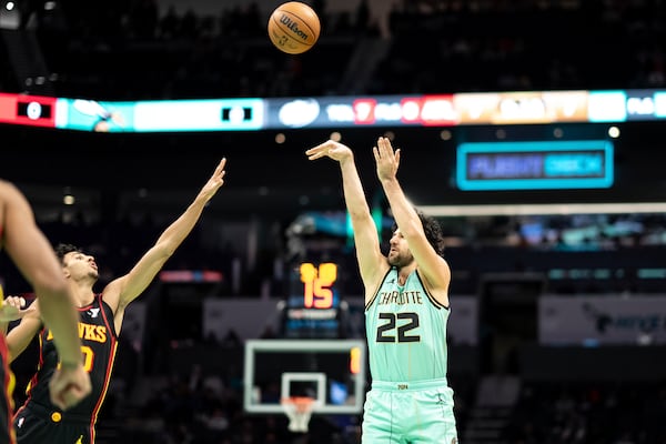 Charlotte Hornets guard Vasilije Micic (22) shoots a three-point basket over Atlanta Hawks forward Zaccharie Risacher (10) during the first half of an NBA basketball game, Saturday, Nov. 30, 2024, in Charlotte, N.C. (AP Photo/Matt Kelley)