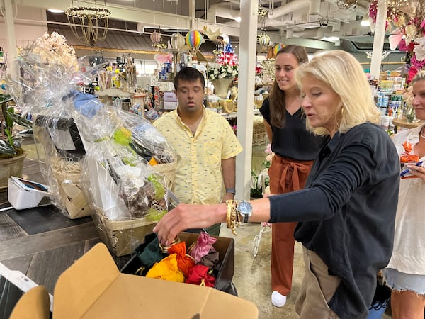 Angad Sahgal (left), who has Down syndrome, has been making cold calls to metro Atlanta stores each week, looking for retailers willing to stock teas imported by his Sandy Springs-based business, Chai Ho Tea. Job coach Caroline Kramer (center) helped on a recent trip he made to Lucy’s Market in Buckhead, where shop owner Kim Wilson (foreground) heard his pitch. (Matt Kempner / mkempner@ajc.com )