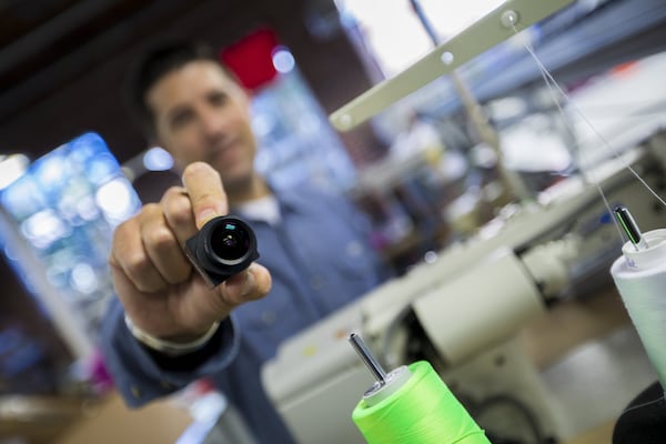 Sewbot machines will be used in a new garment plant in Arkansas to make T-shrits, bringing 400 jobs back to the U.S. Pete Santora, chief commercial officer for SoftWear Automation, holds a lens that allows the company’s Sewbots to get visual input from the manufacturing process. (Courtesy of SoftWear Automation)