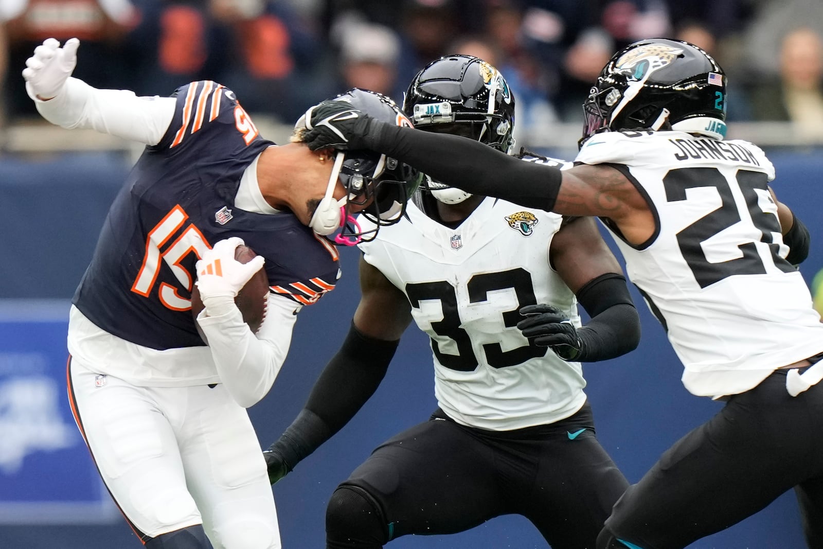 Chicago Bears wide receiver Rome Odunze (15) is tackled by Jacksonville Jaguars linebacker Devin Lloyd (33) and Jaguars safety Antonio Johnson (26) during an NFL football game at the Tottenham Hotspur stadium between the Jacksonville Jaguars and Chicago Bears in London, Sunday, Oct. 13, 2024. (AP Photo/Alastair Grant)