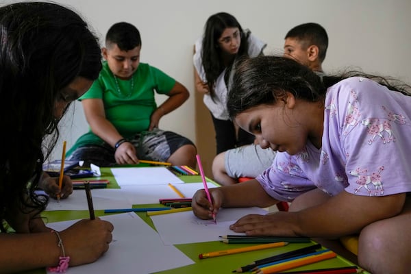 Displaced children draw during a mental healthcare session organized by Doctors Without Borders in an empty building complex housing them, in Beirut, Lebanon, Wednesday, Oct. 9, 2024. (AP Photo/Bilal Hussein)