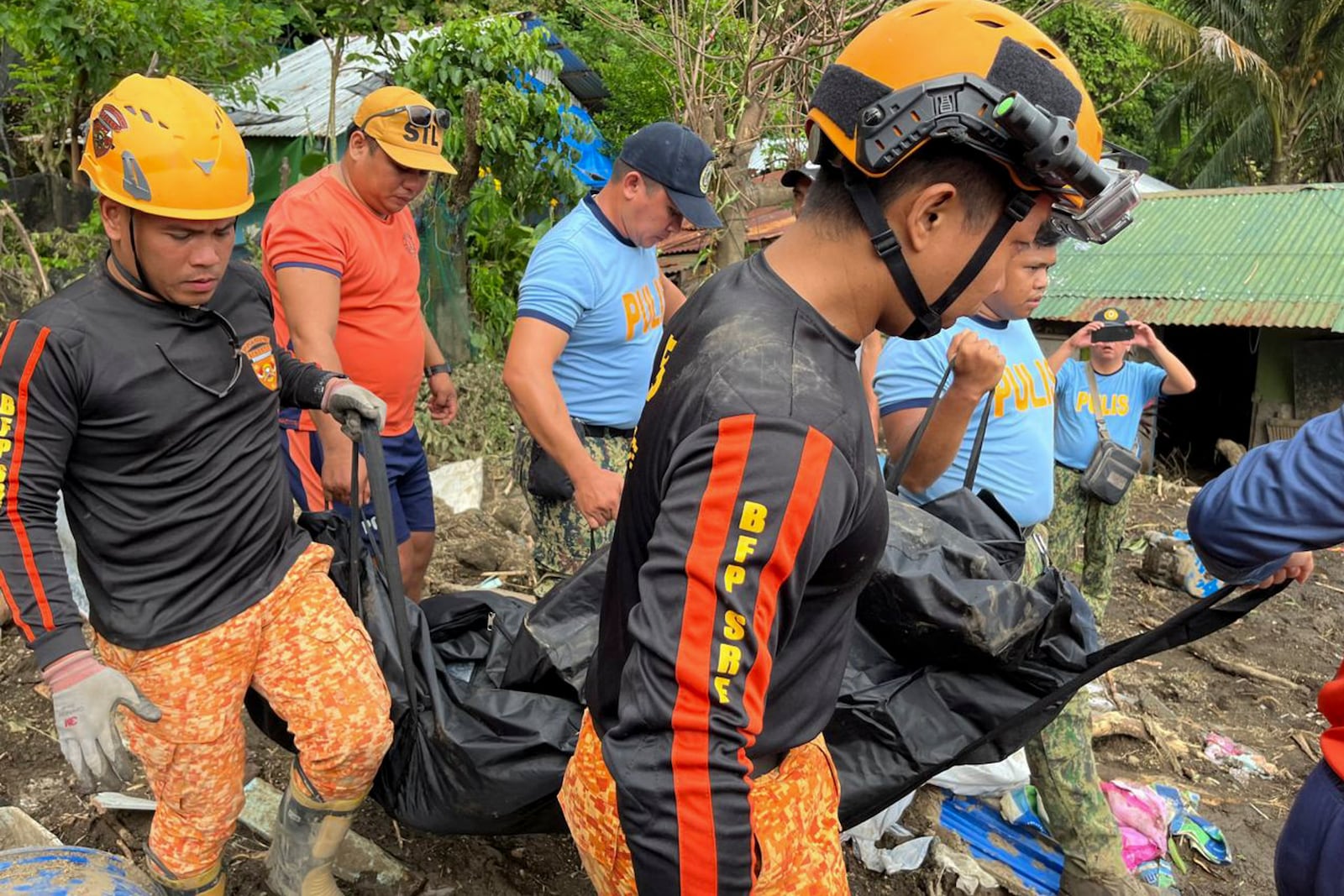 Rescuers carry a body during retrieval operations after a landslide triggered by Tropical Storm Trami, struck homes in Talisay, Batangas province, Philippines, Saturday, Oct. 26, 2024. (AP Photo/Jim Gomez)