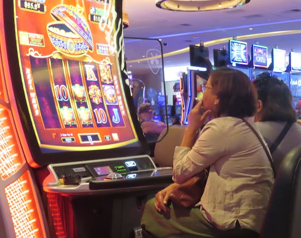 A gambler smokes while playing a slot machine at the Hard Rock casino in Atlantic City N.J. on Aug. 8, 2022. (AP Photo/Wayne Parry)