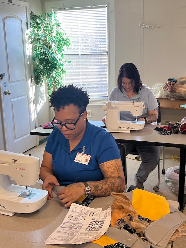 Candice Boles sews quilt blocks together in quilting class at the Women's Transition Center in South DeKalb County. Behind her Shannon Waters works on her own project 
(Courtesy HeartBound Ministries)