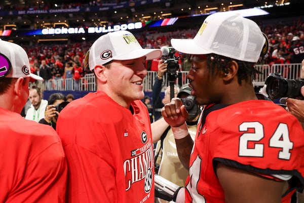 Georgia quarterback Gunner Stockton (left) celebrates with teammate Malaki Starks (24) after the team's 22-19 overtime victory over Texas in the SEC championship game. (Jason Getz/AJC)