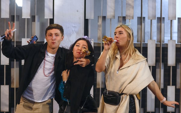 (Left to right) Malcolm Jackson, Anika Rische and Annika Voelpert party during the New Year’s Eve Peach Drop celebration at Underground Atlanta on Saturday, December 31, 2022. (Natrice Miller/natrice.miller@ajc.com)  