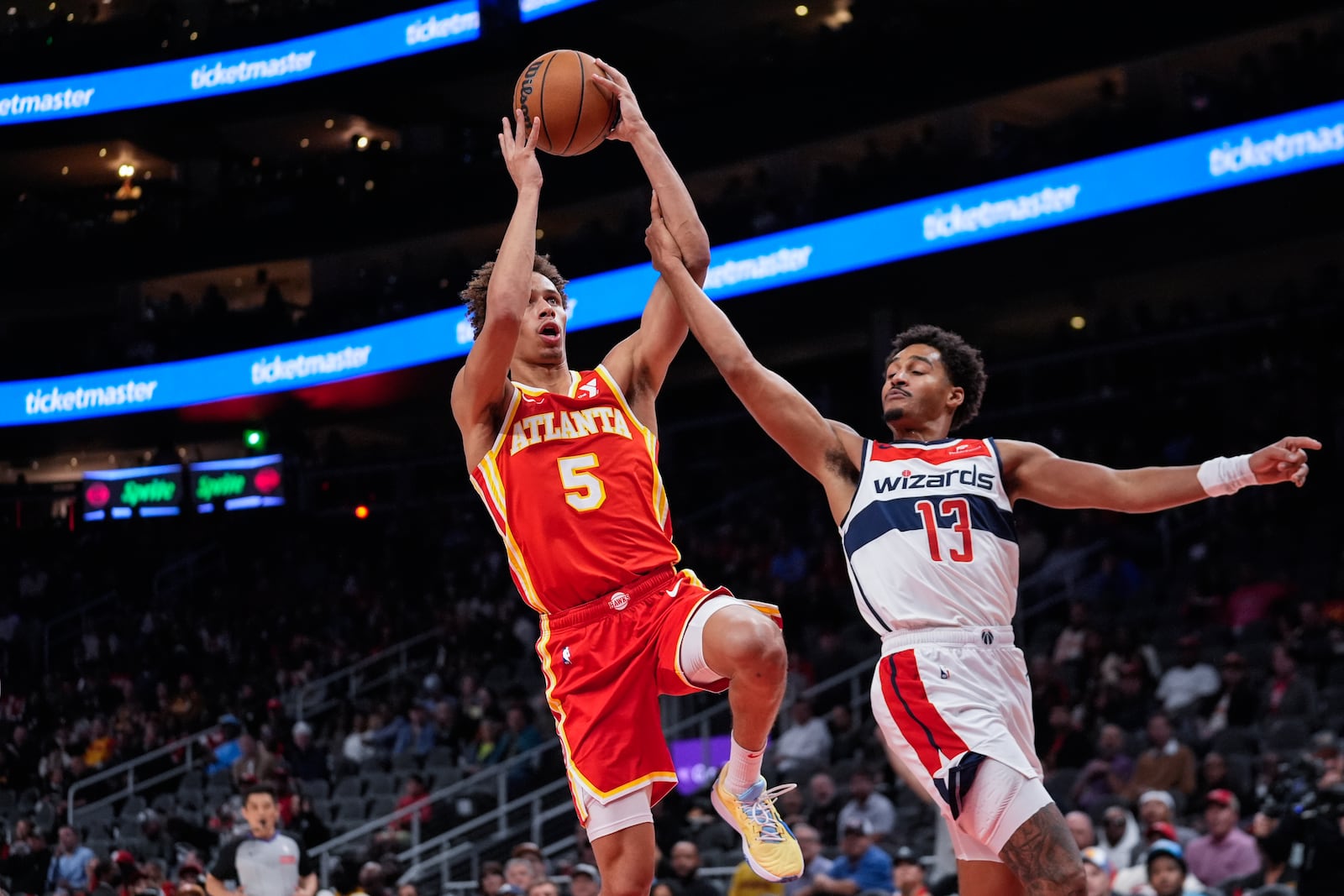 Atlanta Hawks guard Dyson Daniels (5) is fouled by Washington Wizards guard Jordan Poole (13) as he drives to the basket during the first half of an NBA basketball game Monday, Oct. 28, 2024, in Atlanta. (AP Photo/ John Bazemore)