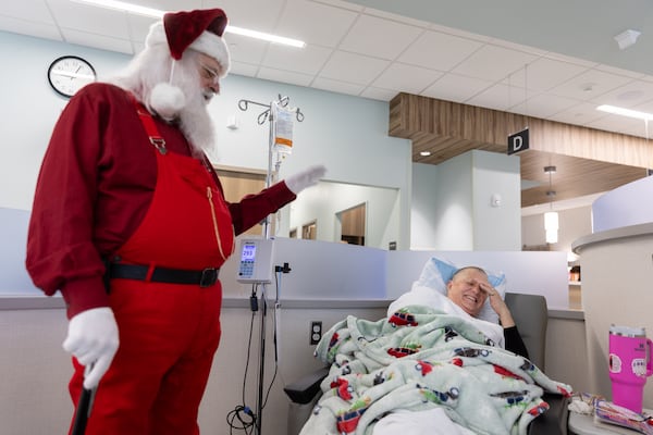 Former patient Jonathan Byrd, who is a favorite local Santa Claus, chats with patient Angela Whitehead at University Cancer & Blood Center in Athens on Wednesday, Dec. 18, 2024. Byrd’s cancer is in remission. (Arvin Temkar/AJC)