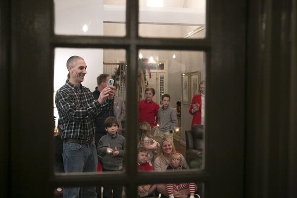 A partygoer takes a photo of people with Santa Claus at a house Christmas party in Smyrna. Judge T. Jackson Bedford, who recently retired as a Fulton County Superior Court judge, has embraced the role of Santa for decades. In this photo, he is at a party at a longtime friend’s house. CASEY SYKES / FOR THE ATLANTA JOURNAL-CONSTITUTION