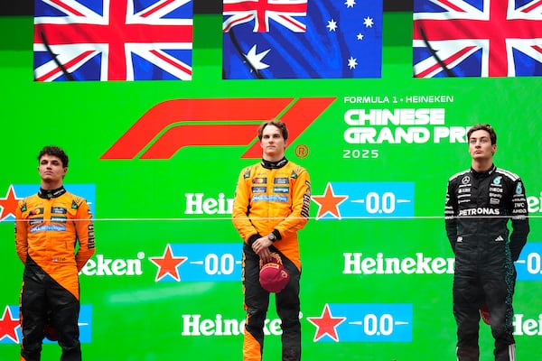 McLaren driver Oscar Piastri of Australia, centre, is flanked on the podium with McLaren driver Lando Norris of Britain, left, and Mercedes driver George Russell of Britain after winning the Chinese Formula One Grand Prix race at the Shanghai International Circuit, Shanghai, Sunday, March 23, 2025. (AP Photo)