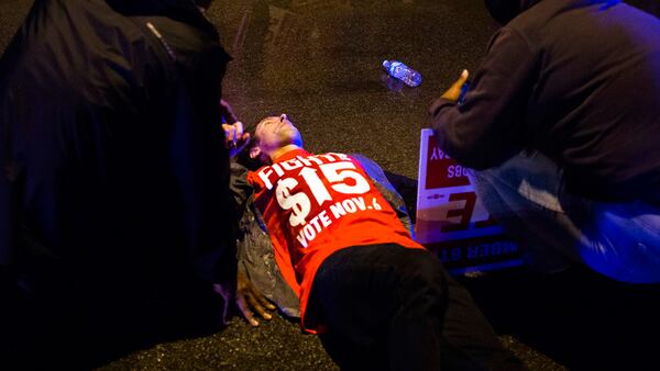 People gather to tend to a protester lying on the ground after a truck collided with into protesters calling for the right to form unions Tuesday, Oct. 2, 2018, in Flint, Mich. Police said the collision appears to be an accident.