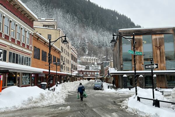 A woman walks down a main street in downtown Juneau, Alaska, on Monday, Dec. 2, 2024, as the city was beginning to dig out from a storm that dumped heavy snow. (AP Photo/Becky Bohrer)