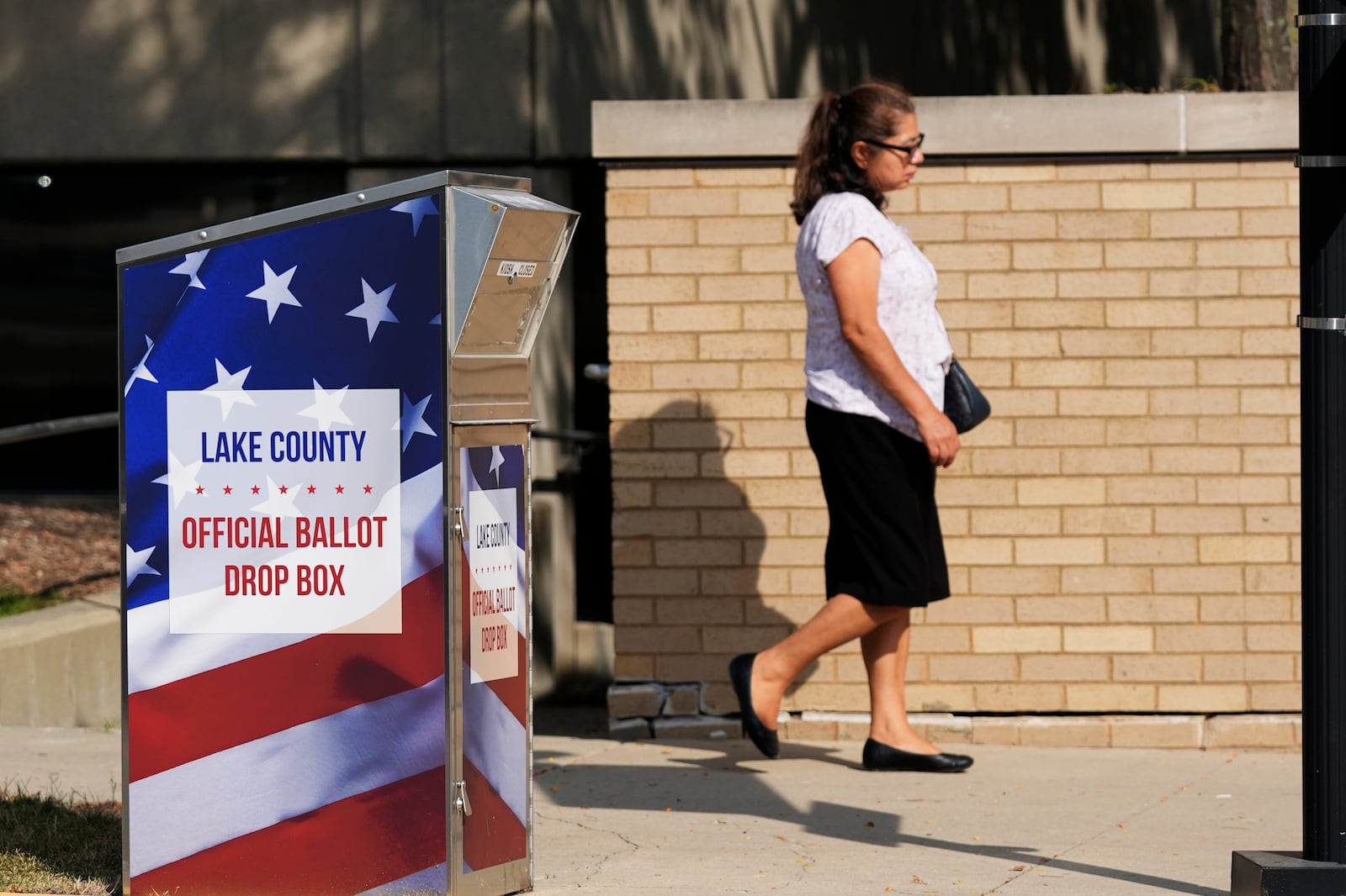 A person walks past a ballot drop-box for Lake County in downtown Waukegan in Waukegan, Ill., Monday, Sept. 16, 2024. (AP Photo/Nam Y. Huh)