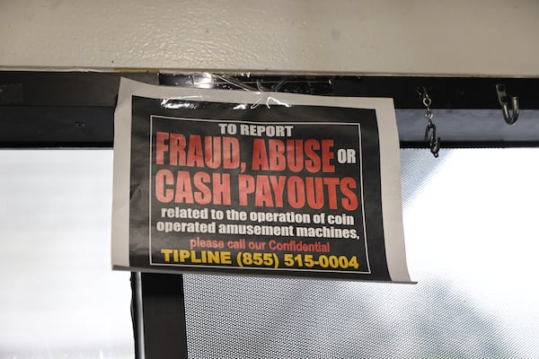 A sign with a tip line phone number for lottery slot machine fraud hangs inside of a gas station in Atlanta. (Natrice Miller/natrice.miller@ajc.com)