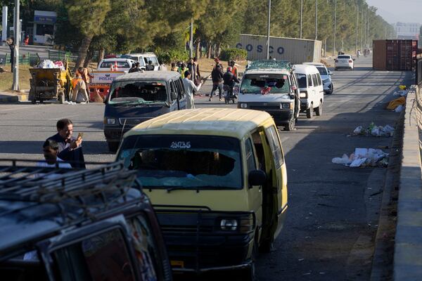 People look at the damaged vehicles left behind by supporters of imprisoned former Prime Minister Imran Khan's Pakistan Tehreek-e-Insaf party when security forces launched an operation Tuesday night to disperse them, in Islamabad, Pakistan, Wednesday, Nov. 27, 2024. (AP Photo/Anjum Naveed)