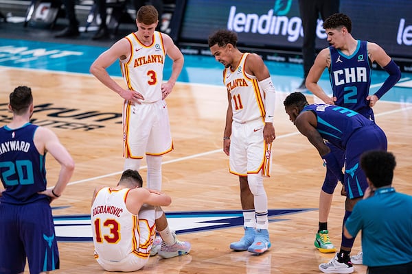 Atlanta Hawks guard Bogdan Bogdanovic (13) sits on the court after being fouled by Charlotte Hornets guard LaMelo Ball (2) during the first half Saturday, Jan. 9, 2021, in Charlotte, N.C. Bogdanovic injured his right knee. (Jacob Kupferman/AP)