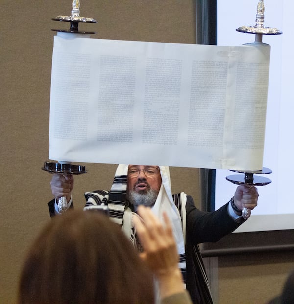 Eyal Postelnik holds up the historic Torah scroll during a celebration of its completion at Chabad of Cobb on Sunday, March 8, 2020.  (Photo: STEVE SCHAEFER / SPECIAL TO THE AJC)