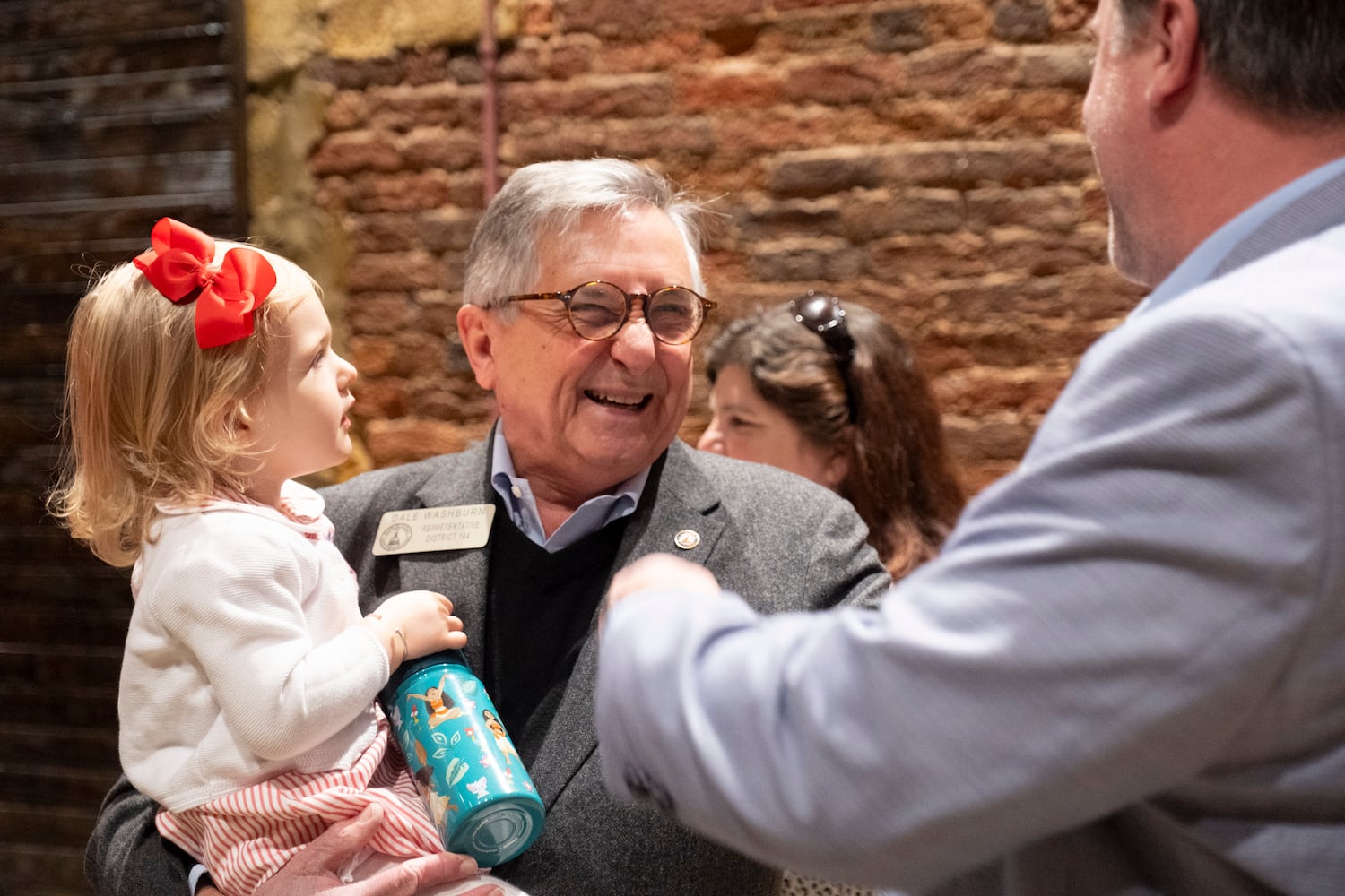 Rep. Dale Washburn (R-Macon) holds his youngest granddaughter, Rosalie Anne, 2, as he socializes at the Wild Hog Supper, which is the traditional kick off to the legislative session in Atlanta on Sunday, Jan. 7, 2024.   (Ben Gray / Ben@BenGray.com)