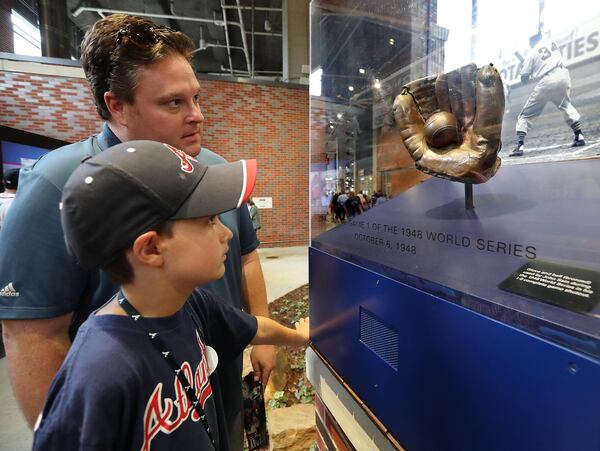 Gavi and his dad Todd Surden take in a display of the bronzed ball and glove used by John Sain during the 1948 World Series while attending the baseball game against the Mets as part of the Braves Exceptional Fans Program at SunTrust Park on May 29 in Atlanta. Curtis Compton/ccompton@ajc.com