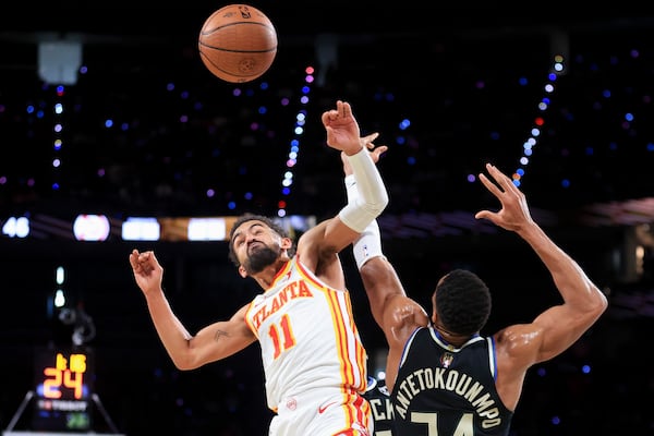 Atlanta Hawks guard Trae Young (11) collides with Milwaukee Bucks forward Giannis Antetokounmpo, right, while contesting for a rebound during the first half of a semifinal game in the NBA Cup basketball tournament Saturday, Dec. 14, 2024, in Las Vegas. (AP Photo/Ian Maule)