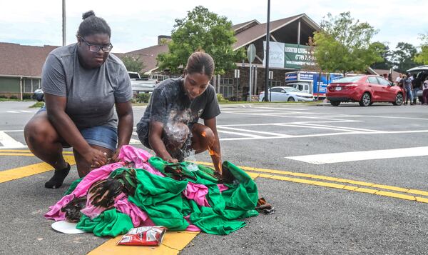 July 16, 2021: Acworth: Tranquil Gardens employees, Kourtland Echols (left) and Chrisheuna Langston (right) burn their uniforms and their co-workers uniforms at Noon after all the residents were to have been moved out of Tranquil Gardens Assisted Living and Memory Care located at 330 Tranquil Gardens Drive in Acworth by Noon on Friday, July 16, 2021 (John Spink / John.Spink@ajc.com)

