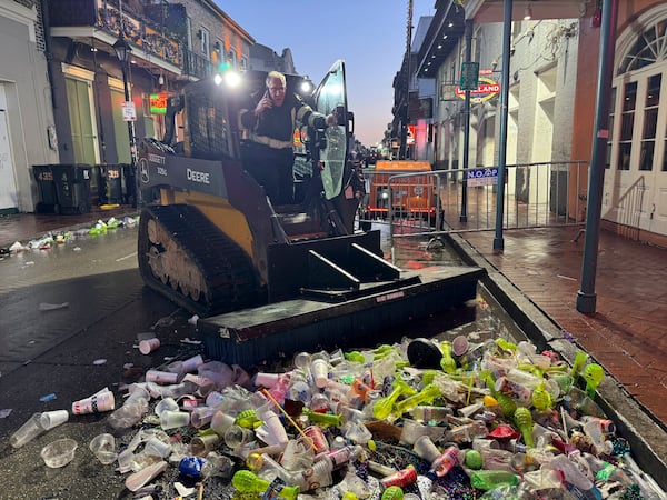 Joe Luscy, an employee with IV Waste, the company tasked with cleaning up the French Quarter after Mardi Gras, coordinates logistics on Ash Wednesday, March 5, 2025, amid a pile of garbage. (AP Photo/Jack Brook)