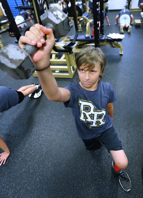 A year older and growing stronger, Bronco Reese lifts weights with teammates during football practice at River Ridge High School in June in Woodstock. CURTIS COMPTON / CCOMPTON@AJC.COM