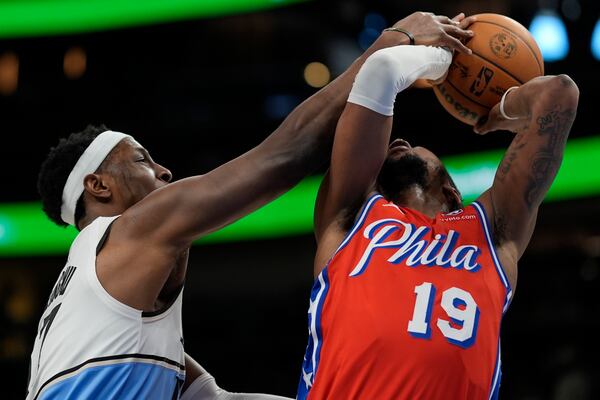 Philadelphia 76ers forward Justin Edwards (19) shoots against Atlanta Hawks forward Onyeka Okongwu (17) during the first half of an NBA basketball game, Sunday, March 23, 2025, in Atlanta. (AP Photo/Mike Stewart)