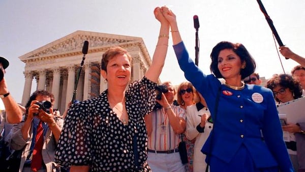 FILE - In this Wednesday, April 26, 1989 file photo, Norma McCorvey, Jane Roe in the 1973 court case, left, and her attorney Gloria Allred hold hands as they leave the Supreme Court building in Washington after sitting in while the court listened to arguments in a Missouri abortion case.  (AP Photo/J. Scott Applewhite, File)