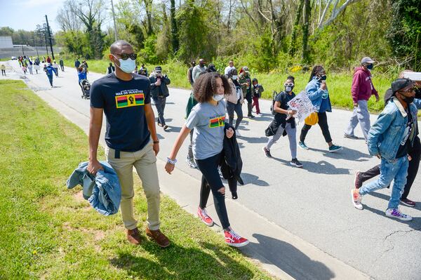 Peachtree City residents Abdou Bah (left) and his daughter Saratou Bah (right) march with other participants as they walk along Bolton Road to the site of the Chattahoochee Brick Company during a sacred event to commemorate the lives lost during the period the company used the convict lease system. The event included a procession, prayers, libations, community testimonials, and site consecration Saturday, April 3, 2021, in Atlanta. (Photo: Daniel Varnado for The Atlanta Journal-Constitution)