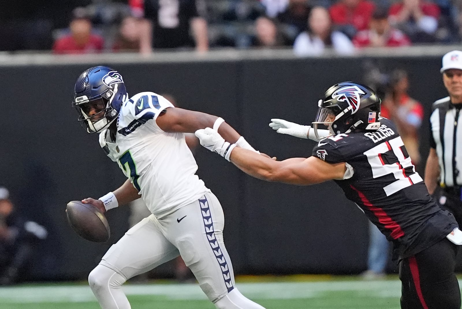 Seattle Seahawks quarterback Geno Smith (7) escapes from Atlanta Falcons linebacker Kaden Elliss (55) during the first half of an NFL football game, Sunday, Oct. 20, 2024, in Atlanta. (AP Photo/ Brynn Anderson )