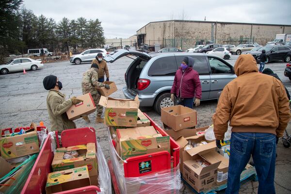 Volunteers and members of the U.S. Army National Guard load groceries at the Hearts to Nourish Hope mobile pantry in Riverdale last month. Though still below pre-pandemic levels, bankruptcies are creeping back up in Georgia in 2021 after a sharp decline last year, the AJC found. (Alyssa Pointer / Alyssa.Pointer@ajc.com)